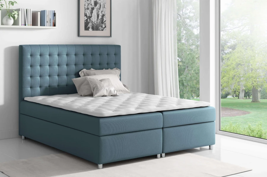 Blaues Boxspringbett mit gestepptem Kopfteil und weißer Matratze