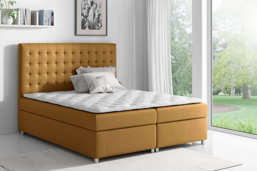 Elegantes Boxspringbett in Senfgelb mit hohem, gestepptem Kopfteil und weißer Matratze.