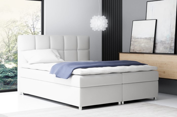 Modernes weißes Boxspringbett mit gestepptem Kopfteil im Schlafzimmer.