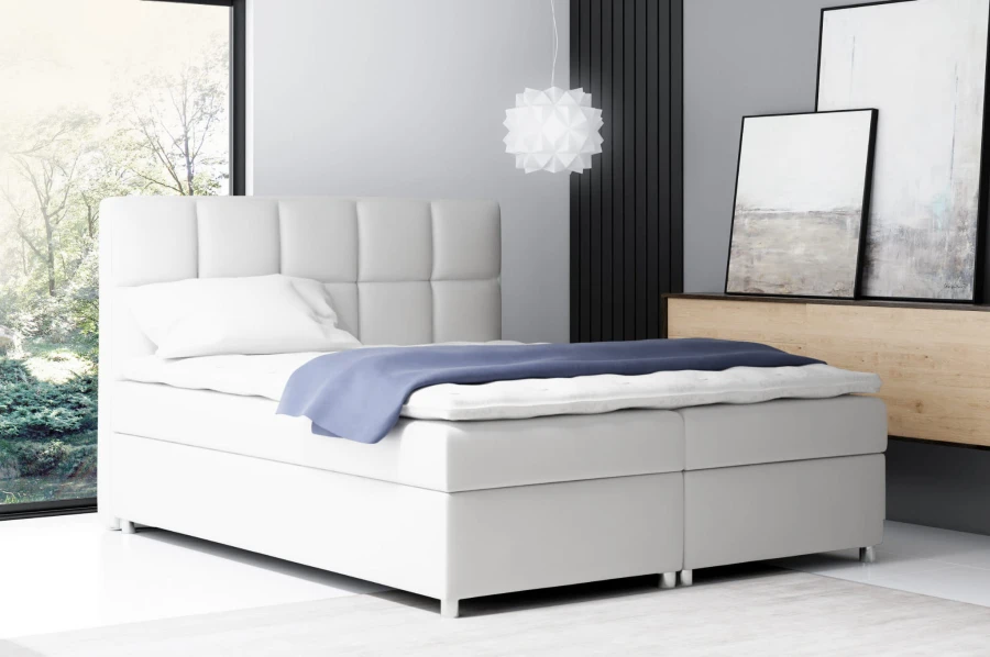 Modernes weißes Boxspringbett mit gepolstertem Kopfteil im Schlafzimmer