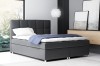 Graues Boxspringbett mit gestepptem Kopfteil und blauer Decke