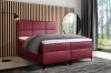 Elegantes bordeauxrotes Boxspringbett vor einer stylischen Holzpaneel-Wand.