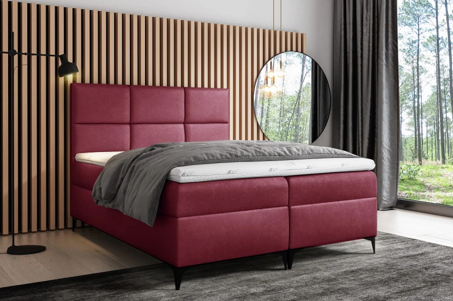 Elegantes bordeauxrotes Boxspringbett vor einer stylischen Holzpaneel-Wand.