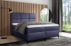 Dunkelblaues Boxspringbett mit Topper und Kissen in modernem Innendesign.