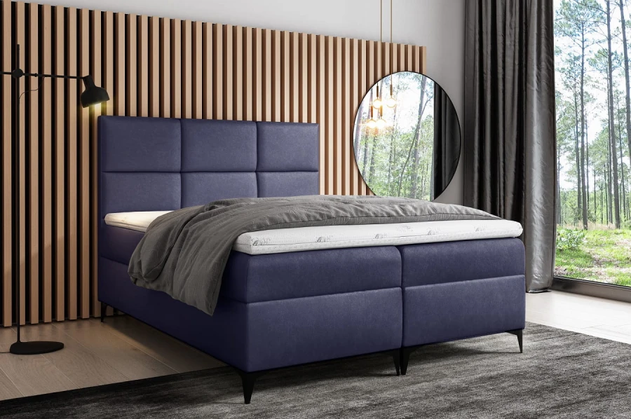 Dunkelblaues Boxspringbett mit Topper und Kissen in modernem Innendesign.