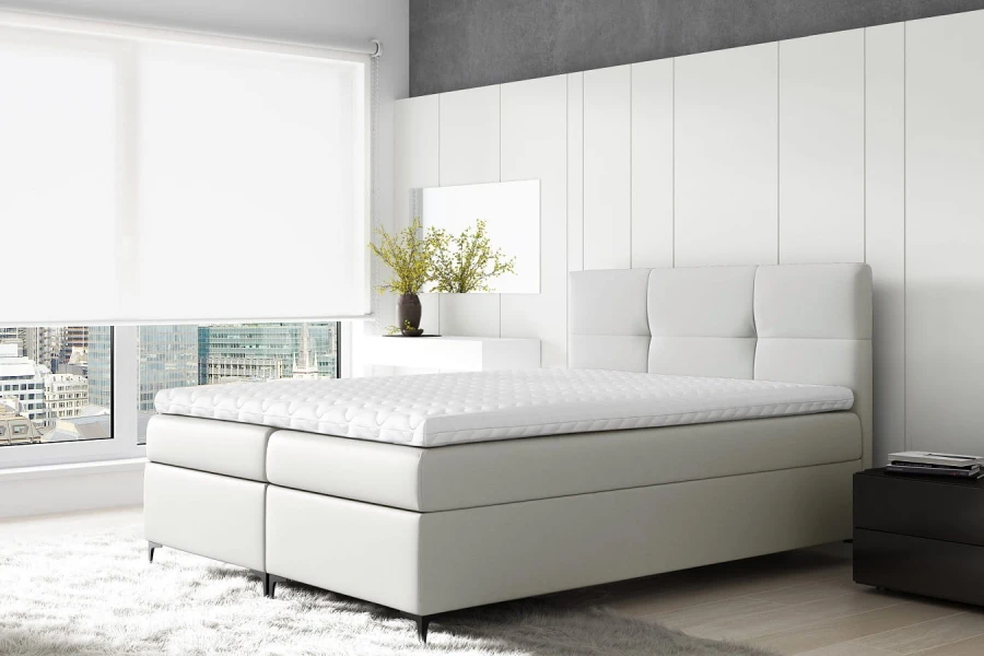 Elegantes weißes Boxspringbett in modernem, hellem Schlafzimmer mit Stadtblick.