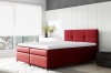 Stilvolles rotes Boxspringbett als Farbakzent in hellem Schlafzimmer vor Stadtpanorama.