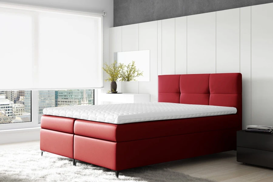Stilvolles rotes Boxspringbett als Farbakzent in hellem Schlafzimmer vor Stadtpanorama.