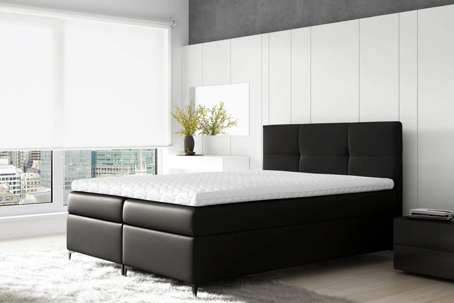 Modernes schwarzes Boxspringbett mit gepolstertem Kopfteil und weißem Topper im hellen Zimmer.