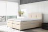 Modernes beiges Boxspringbett mit weißem Topper in hellem Schlafzimmer Ambiente