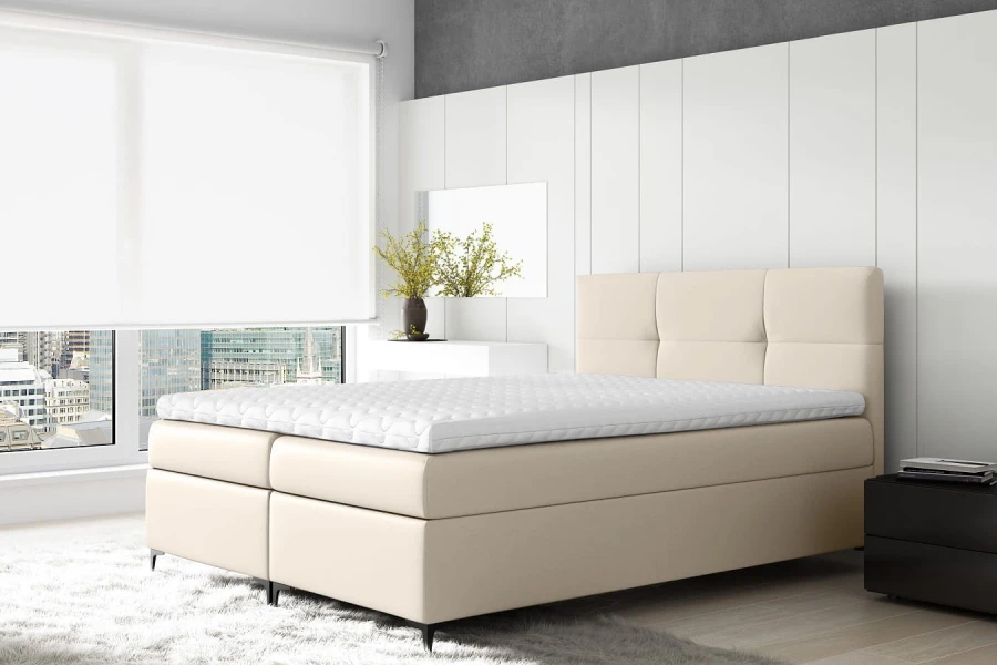 Modernes beiges Boxspringbett mit weißem Topper in hellem Schlafzimmer Ambiente