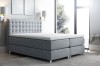 Graues Boxspringbett mit gestepptem Kopfteil im modernen Schlafzimmer-Ambiente.