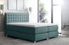 Türkisfarbenes Boxspringbett mit elegantem Polsterkopfteil und bequemem Topper.