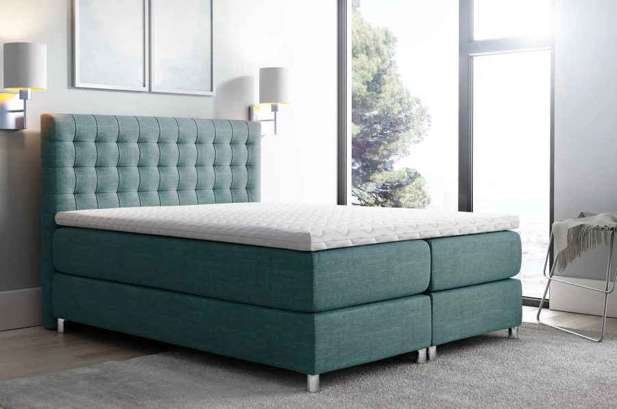 Türkisfarbenes Boxspringbett mit elegantem Polsterkopfteil und bequemem Topper.