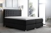 Dunkelgraues Boxspringbett mit hohem, gepolstertem Kopfteil für Schlafkomfort.