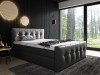 Modernes schwarzes Boxspringbett mit gestepptem Kopfteil und Fußteil im dunklen Schlafzimmer.
