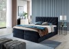 Dunkelblaues Samt-Boxspringbett mit dekorativem Fächer-Kopfteil vor einer blauen Wand.