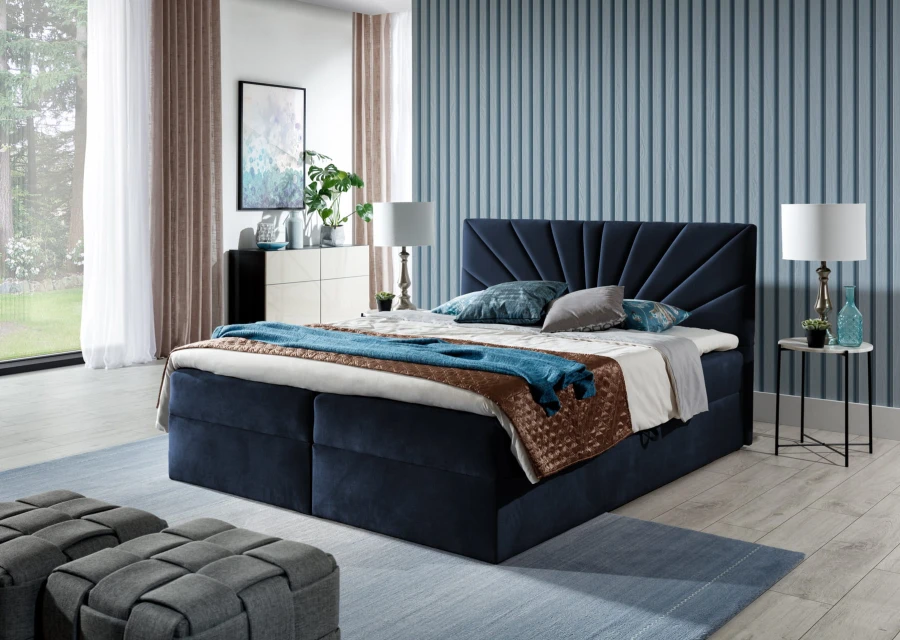 Dunkelblaues Samt-Boxspringbett mit dekorativem Fächer-Kopfteil vor einer blauen Wand.