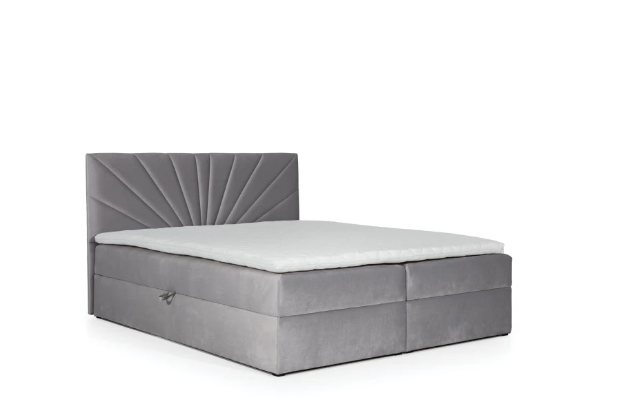 Graues Boxspringbett aus Samt mit strahlenförmig gestepptem Kopfteil vor weißem Hintergrund.