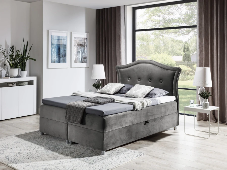 Graues Boxspringbett mit gepolstertem Kopfteil und eleganter Knopfheftung