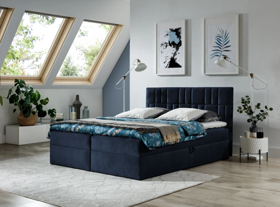 Dunkelblaues Boxspringbett mit Bettkasten in hellem Schlafzimmer unter Dachschrägen