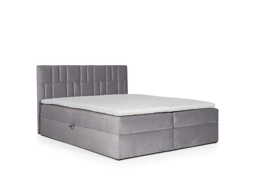 Graues Boxspringbett mit weißem Topper und gestepptem Kopfteil vor weißem Hintergrund