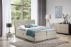 Beiges Boxspringbett mit modernem Kopfteil und Bettwäsche im hellen Zimmer.