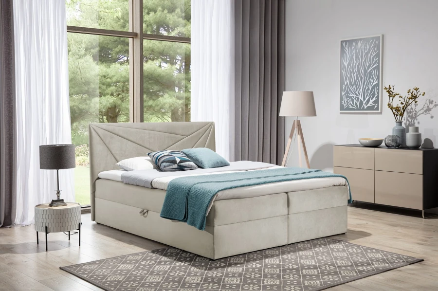 Beiges Boxspringbett mit modernem Kopfteil und Bettwäsche im hellen Zimmer.