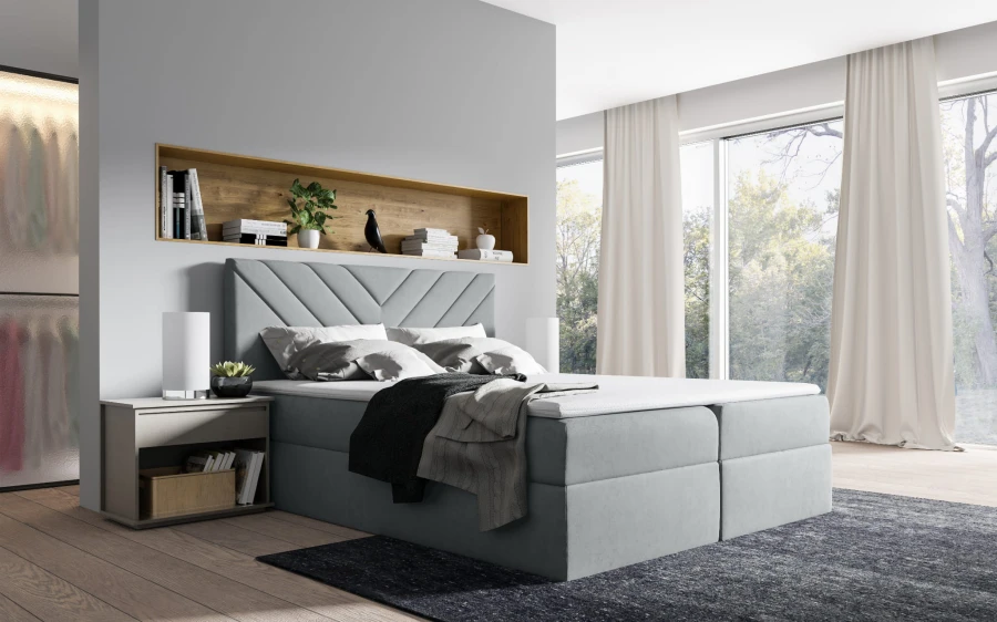 Modernes hellgraues Boxspringbett mit gestepptem Kopfteil in hellem Schlafzimmer.