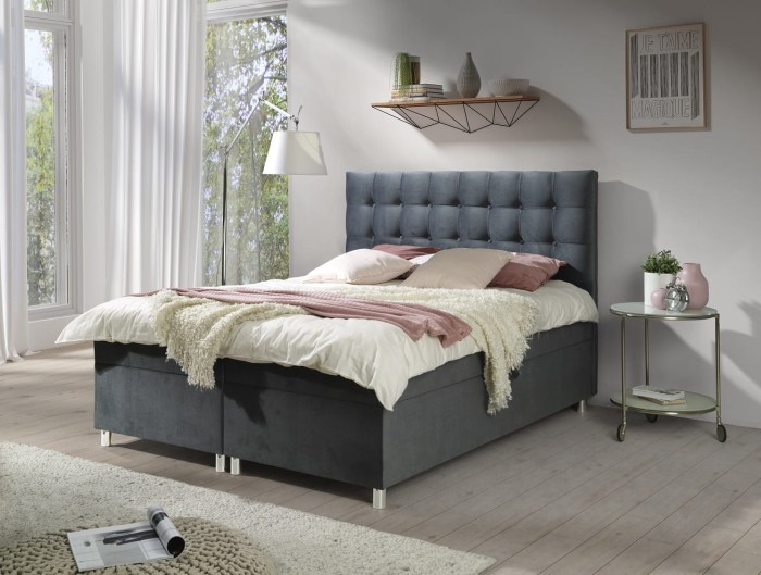 Dunkelgraues Boxspringbett mit dekorativer Knopfheftung am Kopfteil.