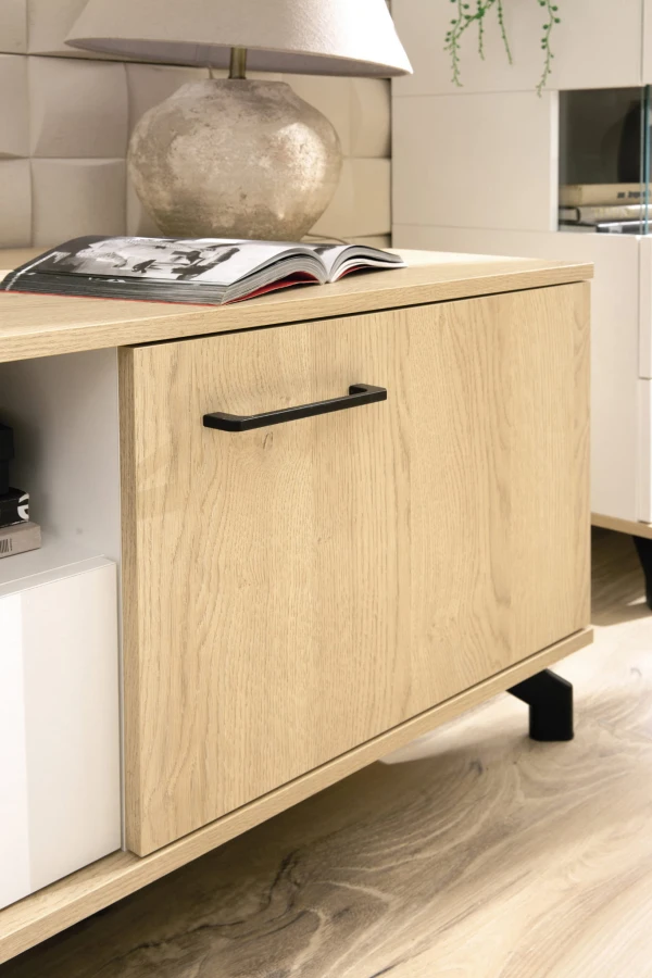 Detailaufnahme eines schwarzen Möbelgriffs auf einer Tür in Eiche-Optik mit dekorativer Maserung.