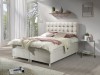 Cremefarbenes Boxspringbett mit gestepptem Kopfteil, moderne Schlafzimmer-Einrichtung.