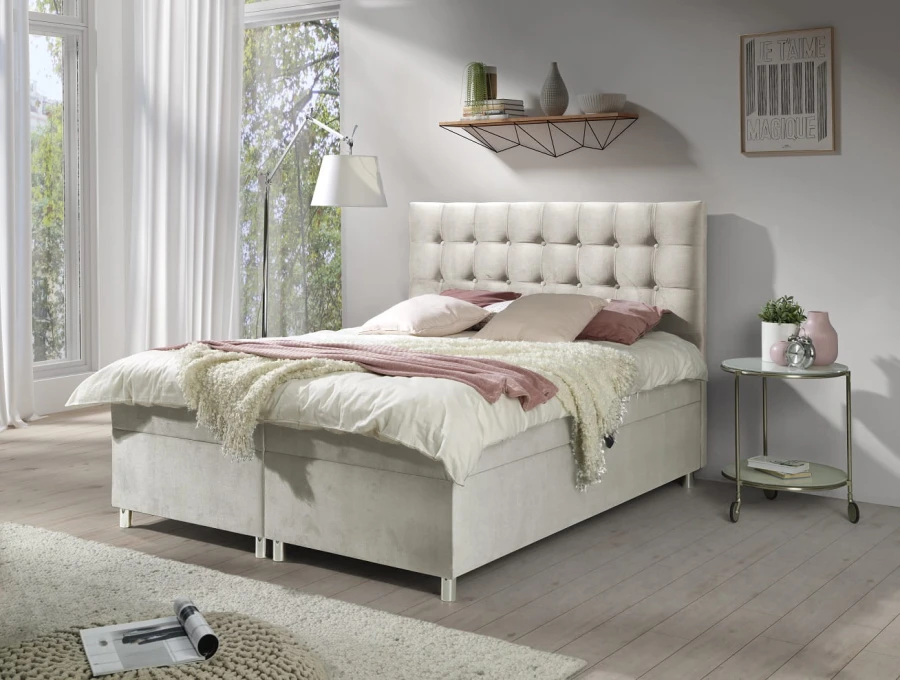 Cremefarbenes Boxspringbett mit gestepptem Kopfteil, moderne Schlafzimmer-Einrichtung.