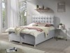 Hellgraues Boxspringbett mit Knopfsteppung am Kopfteil für ein modernes Schlafzimmer.