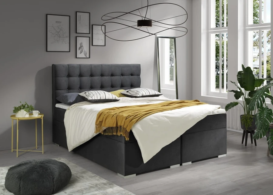 Modernes Boxspringbett in Anthrazit mit gepolstertem Kopfteil und gelber Decke im Schlafzimmer.