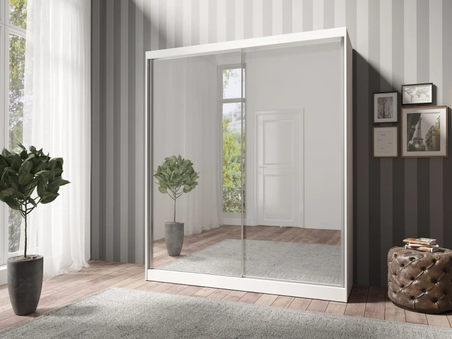 Moderner weißer Schwebetürenschrank mit großen Spiegelfronten in einem hellen Schlafzimmer.