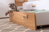 Bettkastenschublade in Eiche-Nachbildung mit Kuscheltier und grünen Kissen unter einem weißen Bett.