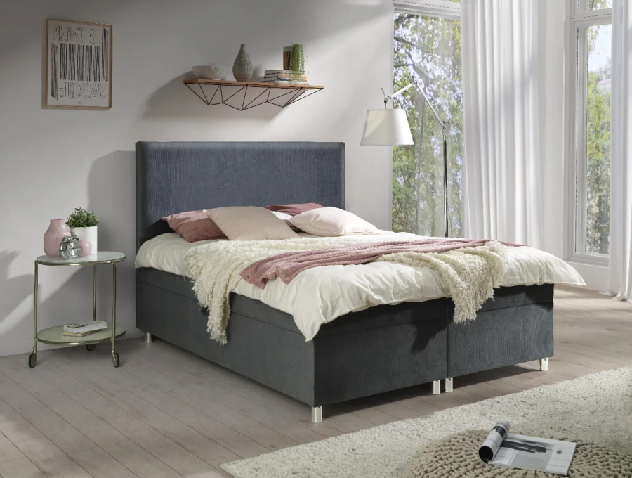 Dunkelgraues Polsterbett mit elegantem Stoffbezug und dekorativen Kissen.