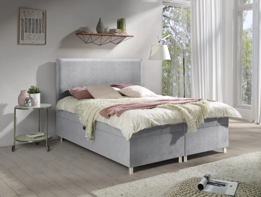 Stilvolles hellgraues Boxspringbett in modern eingerichtetem Schlafzimmer.