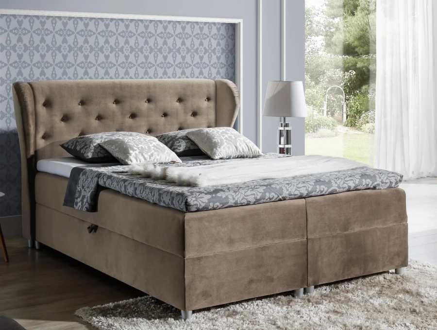 Braunes Boxspringbett mit gestepptem Kopfteil und Bettkasten im Schlafzimmer