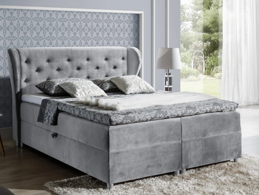 Graues Boxspringbett mit gepolstertem Kopfteil und Knopfheftung im modernen Design