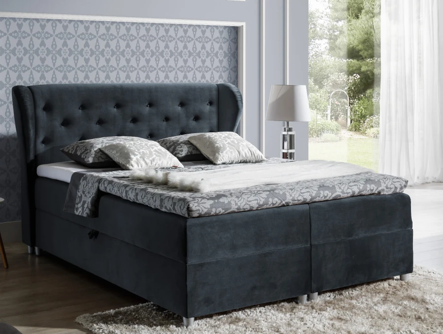 Dunkelblaues Boxspringbett mit gestepptem Kopfteil und eleganter Bettwäsche im modernen Schlafzimmer.