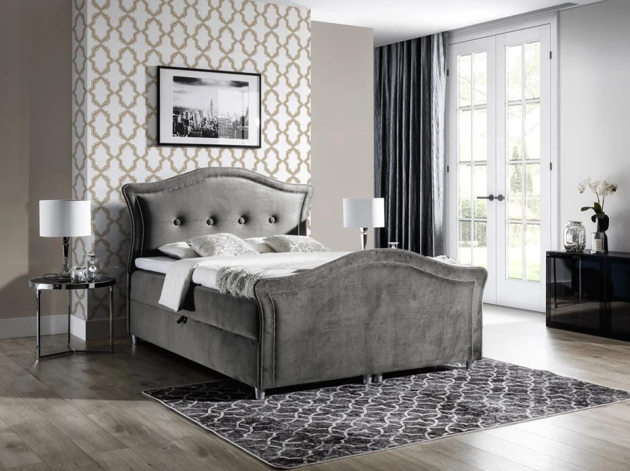 Graues Samtbett mit eleganter Knopfsteppung und geschwungenem Betthaupt für stilvolles Wohnen.