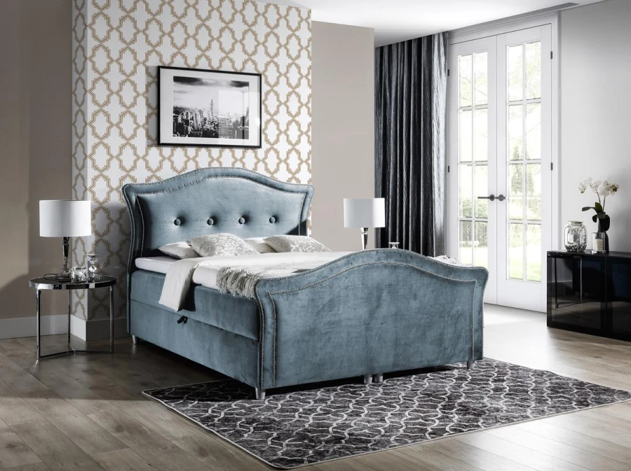 Blaues Polsterbett mit Samtbezug und dekorativer Knopfheftung, geschwungenes Design.