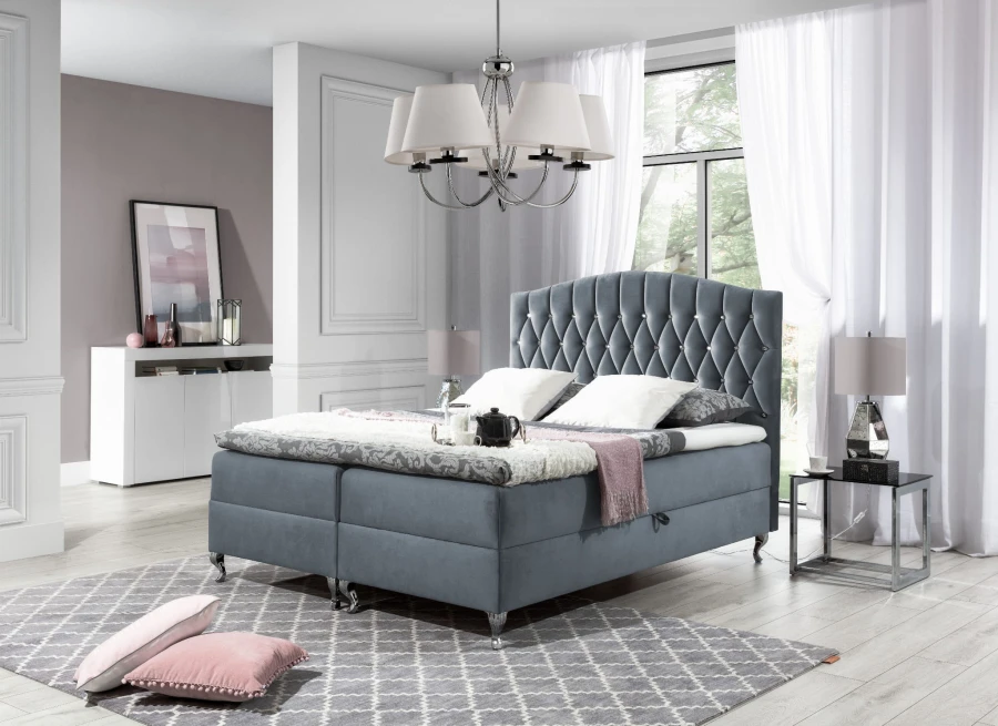 Graues Boxspringbett mit gestepptem Kopfteil und silbernen Füßen in modernem Schlafzimmer.