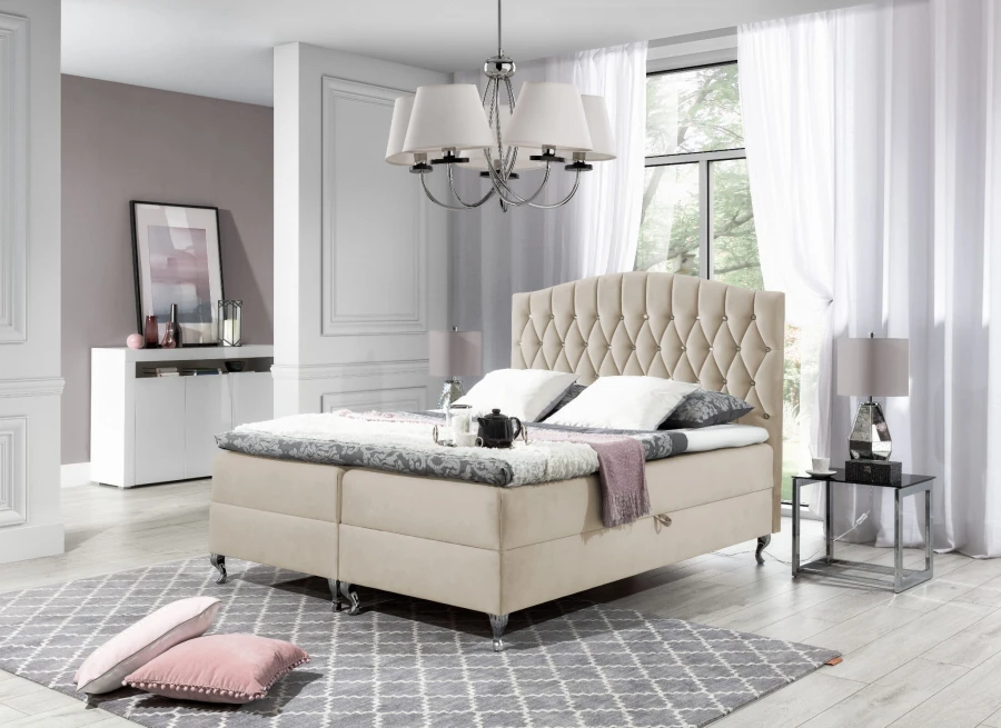 Beiges Boxspringbett mit gestepptem Kopfteil im hellen Schlafzimmer für gemütliches Wohnen.