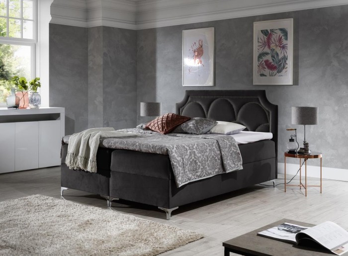 Modernes Boxspringbett in Schwarz mit geschwungenem Kopfteil und Samtbezug.
