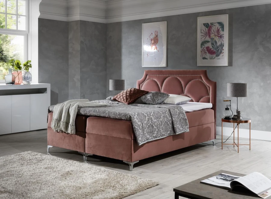 Stilvolles Boxspringbett in Altrosa mit dekorativem Kopfteil und gemütlicher Ausstattung