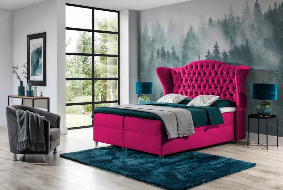 Luxuriöses Boxspringbett in Pink mit hohem Chesterfield-Kopfteil vor Wald-Tapete.