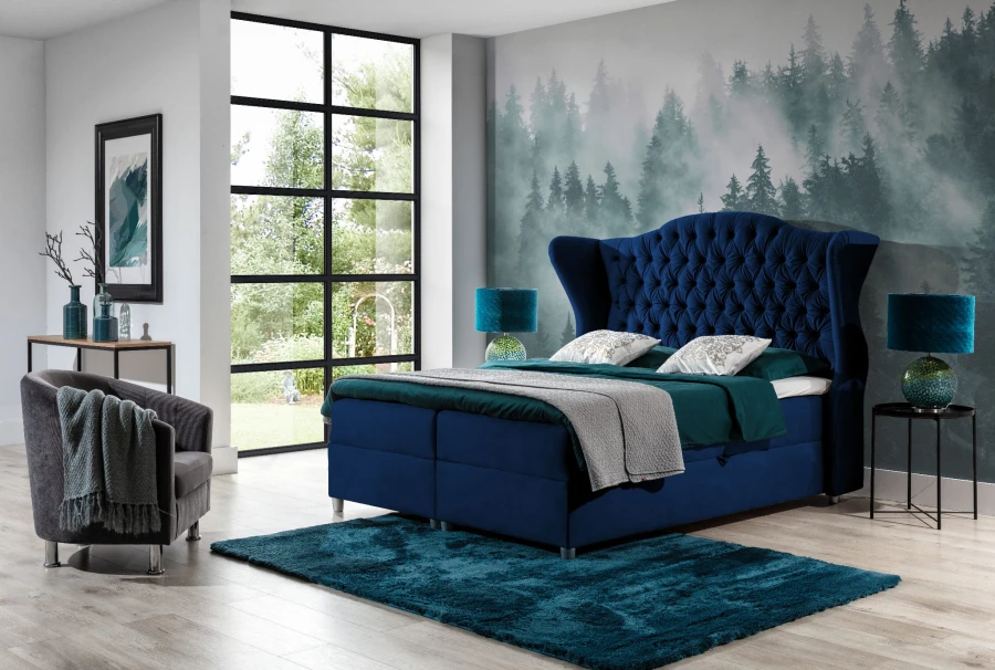 Hochwertiges Boxspringbett in Blau mit gepolstertem Kopfteil und tealfarbenem Teppich.